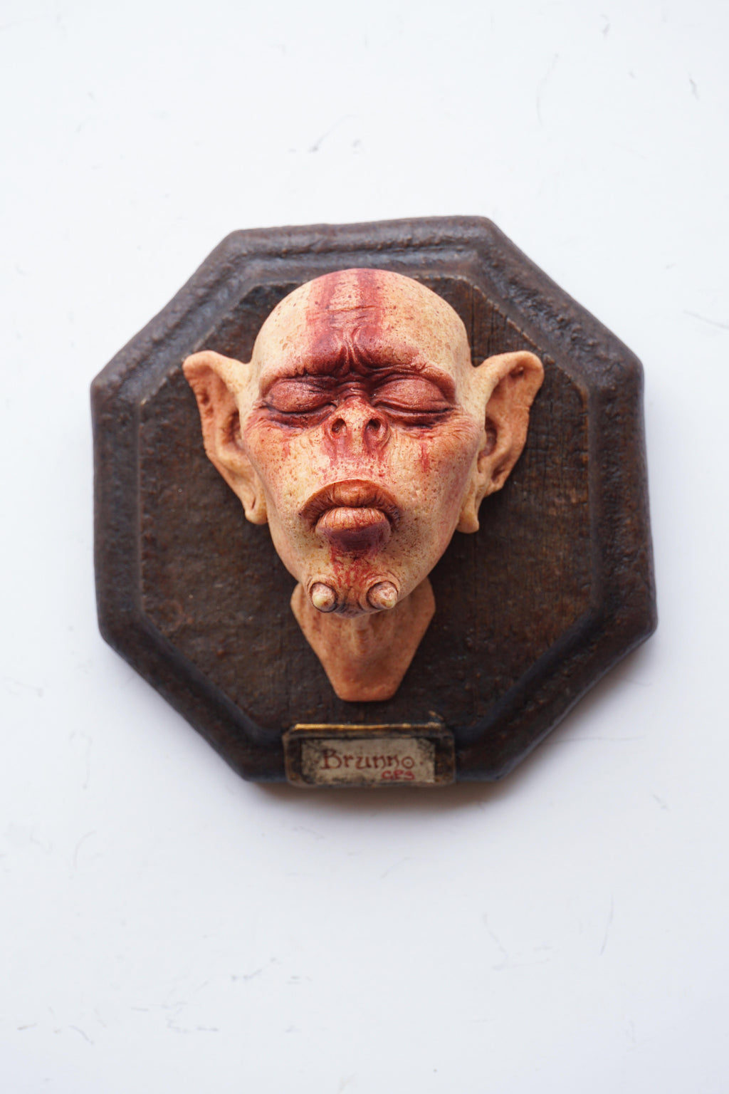 Decorative wall piece with a stylized face on an octagonal wooden frame.
