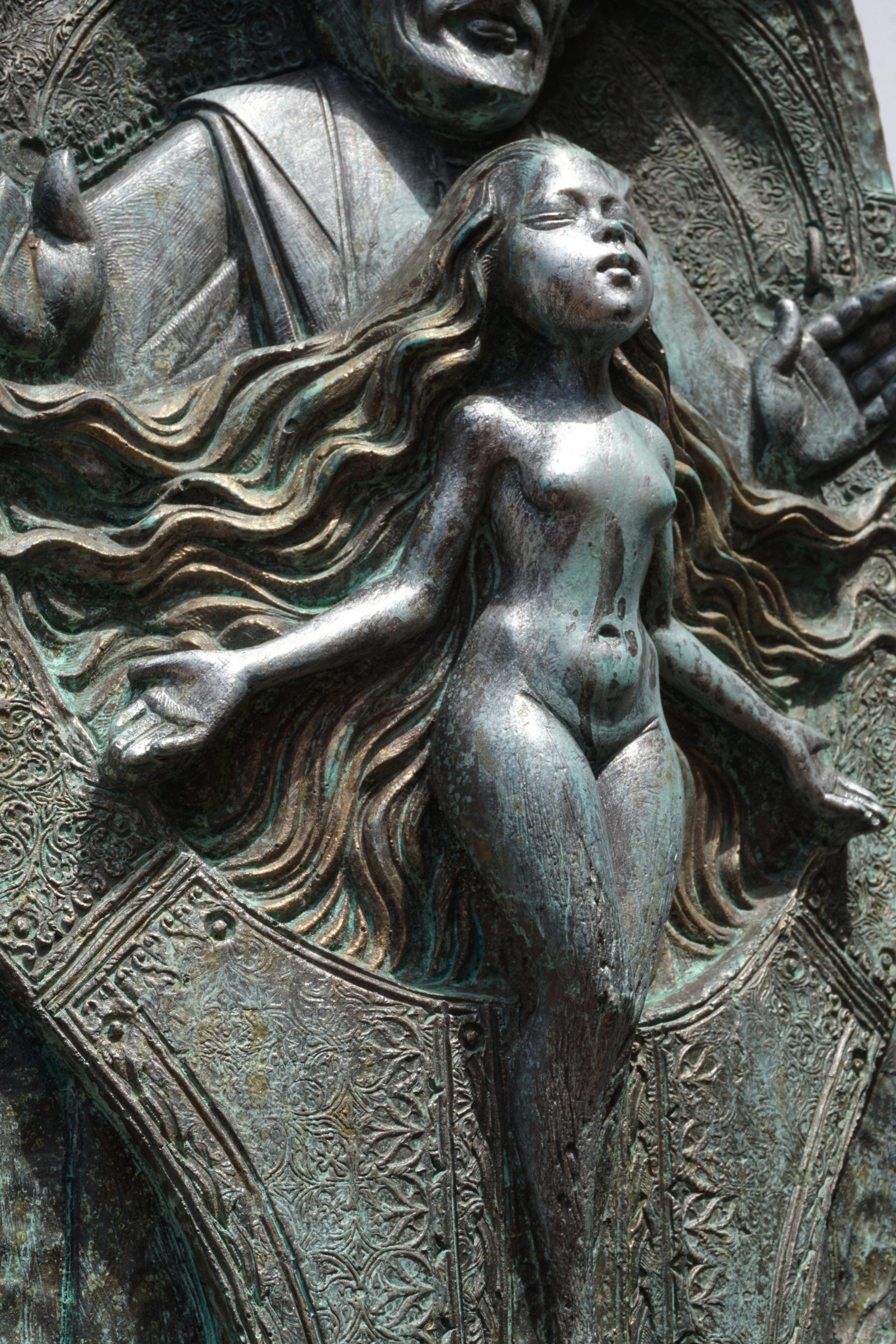 Bronze sculpture of a nude figure with flowing hair and draped fabric