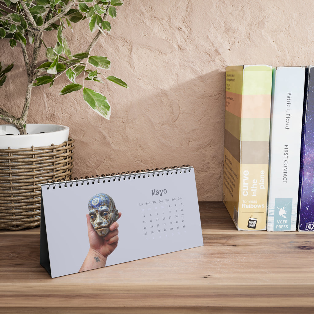 Calendar on a wooden surface with books and a plant in the background