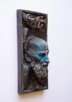 Decorative wall piece with a stylized face on a white background